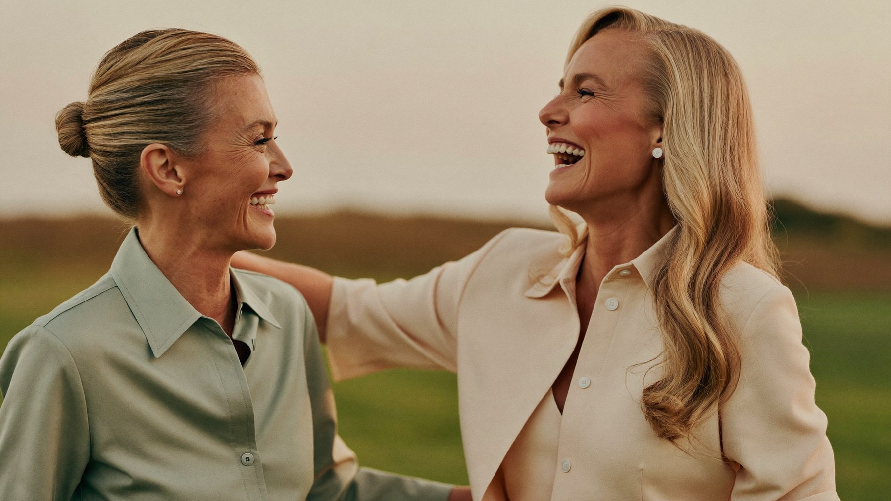 Due donne mature sorridono insieme nella luce calda del tramonto